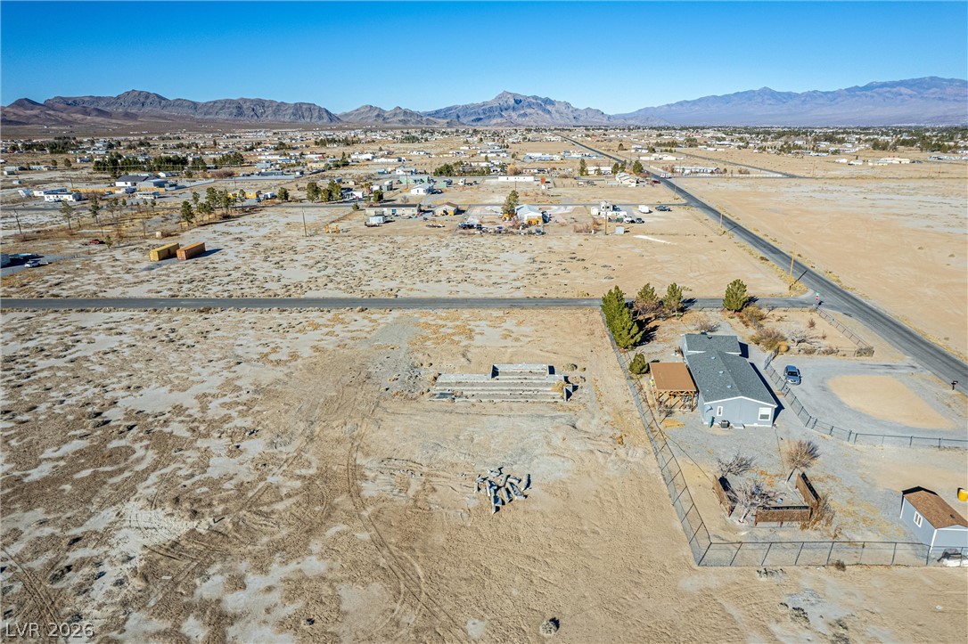 4051 Forest Road Pahrump, NV 89048 - Photo 14 of 15 An aerial perspective reveals a vast, open desert landscape with a distant mountain range and a cozy residential dwelling nestled amidst the terrain.