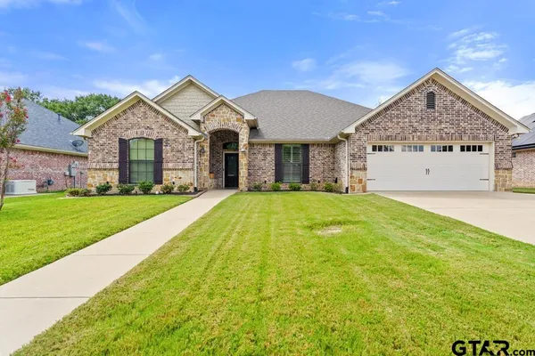 a front view of a house with yard and green space
