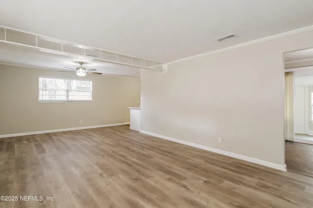 a view of an empty room with wooden floor and a window