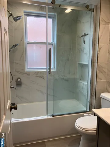 a bathroom with a granite countertop bathtub shower sink vanity and toilet