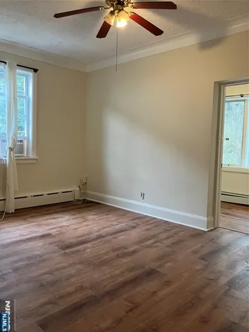 an empty room with wooden floor chandelier fan and windows