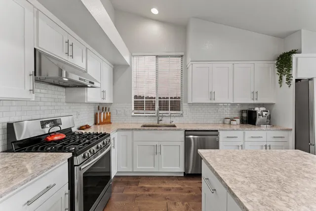 a kitchen with stainless steel appliances granite countertop a sink stove and cabinets