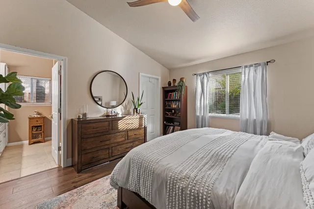 a bedroom with a bed a mirror on dresser and a window