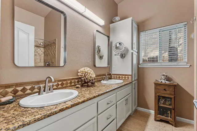 a bathroom with a granite countertop double vanity sinks and a mirror