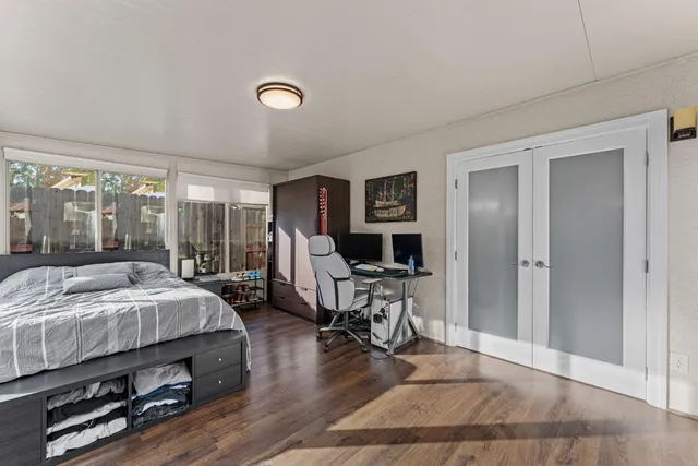 a bedroom with a bed a large window and wooden floor
