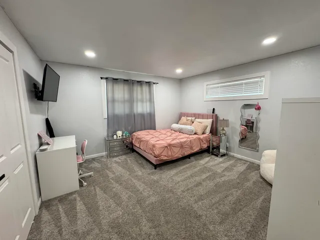 a spacious bedroom with a bed and a flat screen tv
