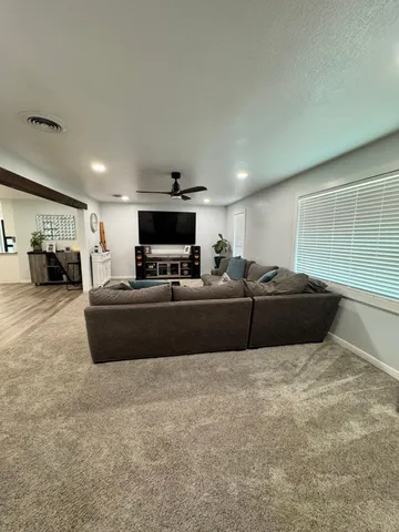 a living room with furniture a flat screen tv and kitchen view