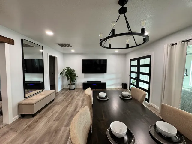 a kitchen with stainless steel appliances a dining table chairs and a wooden floor