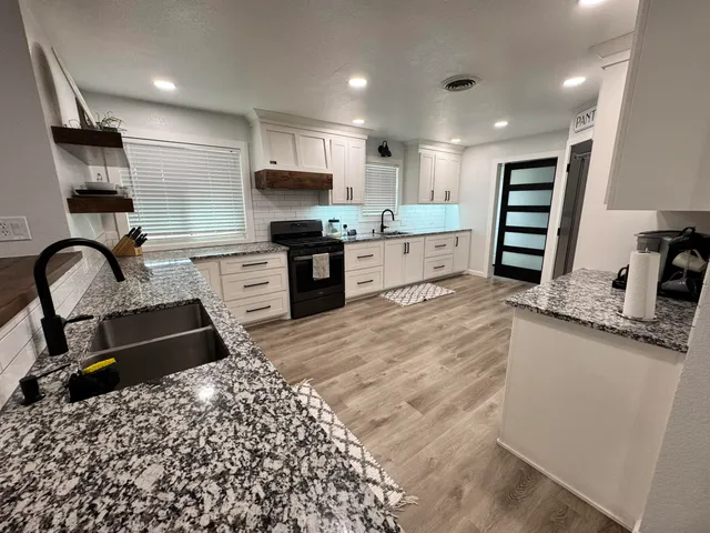 a kitchen with stainless steel appliances kitchen island granite countertop a stove a sink and a refrigerator