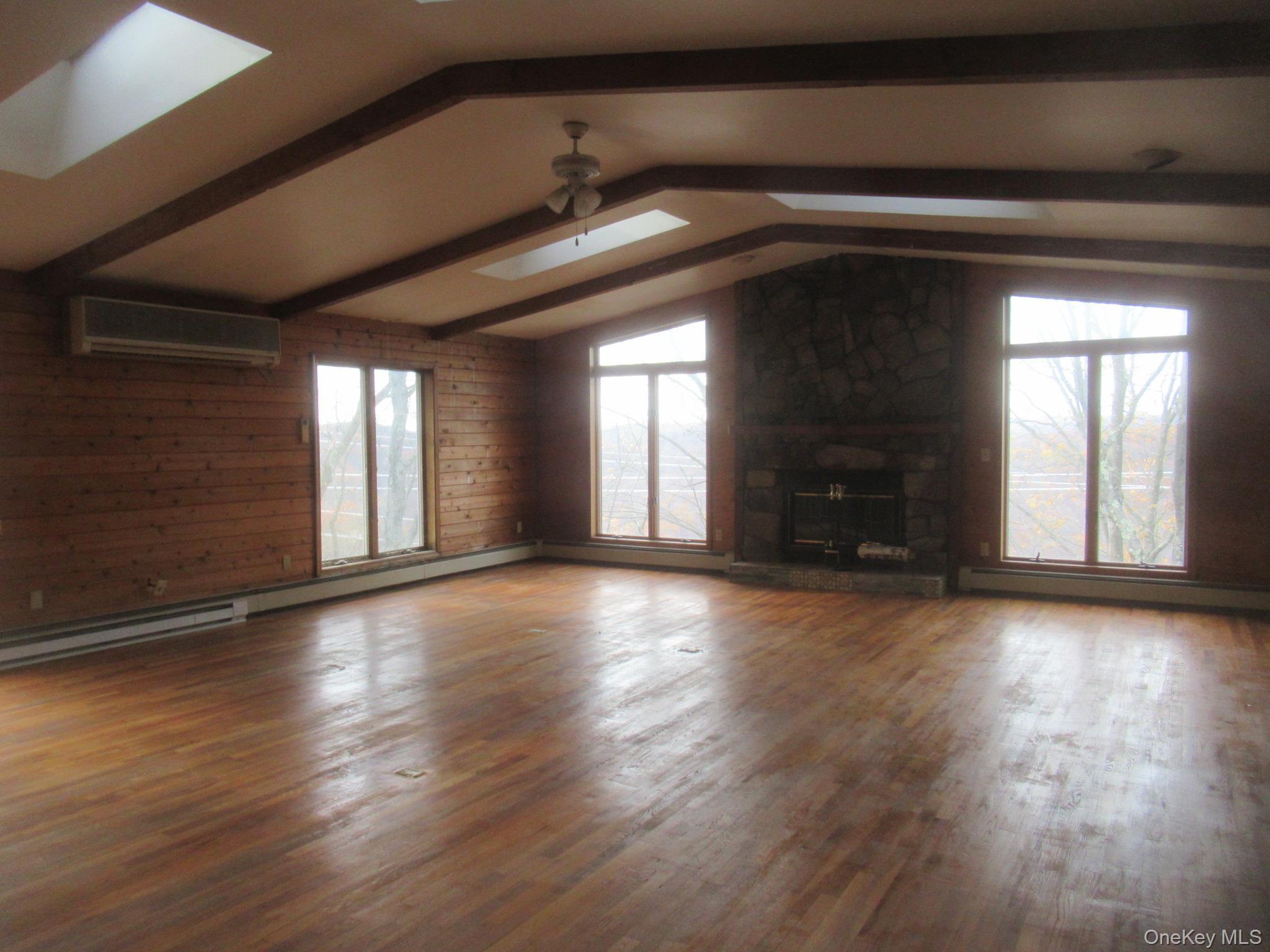64 Hillside View Road Mahopac, NY 10541 - Photo 4 of 25 Unfurnished living room with a skylight, wood finished floors, a baseboard radiator, a wall mounted air conditioner, and baseboard heating