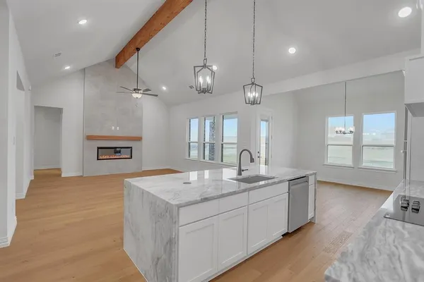 a hall with kitchen island a stove a sink dishwasher and a dining table with wooden floor