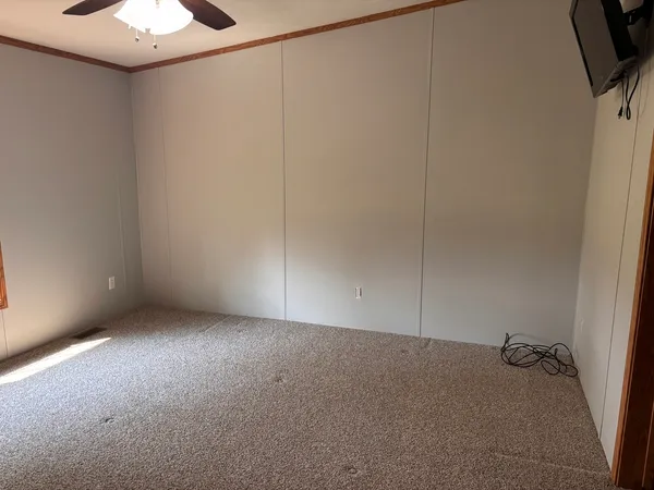 an empty room with a window and a fan