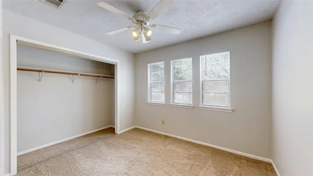an empty room with a chandelier fan and closet