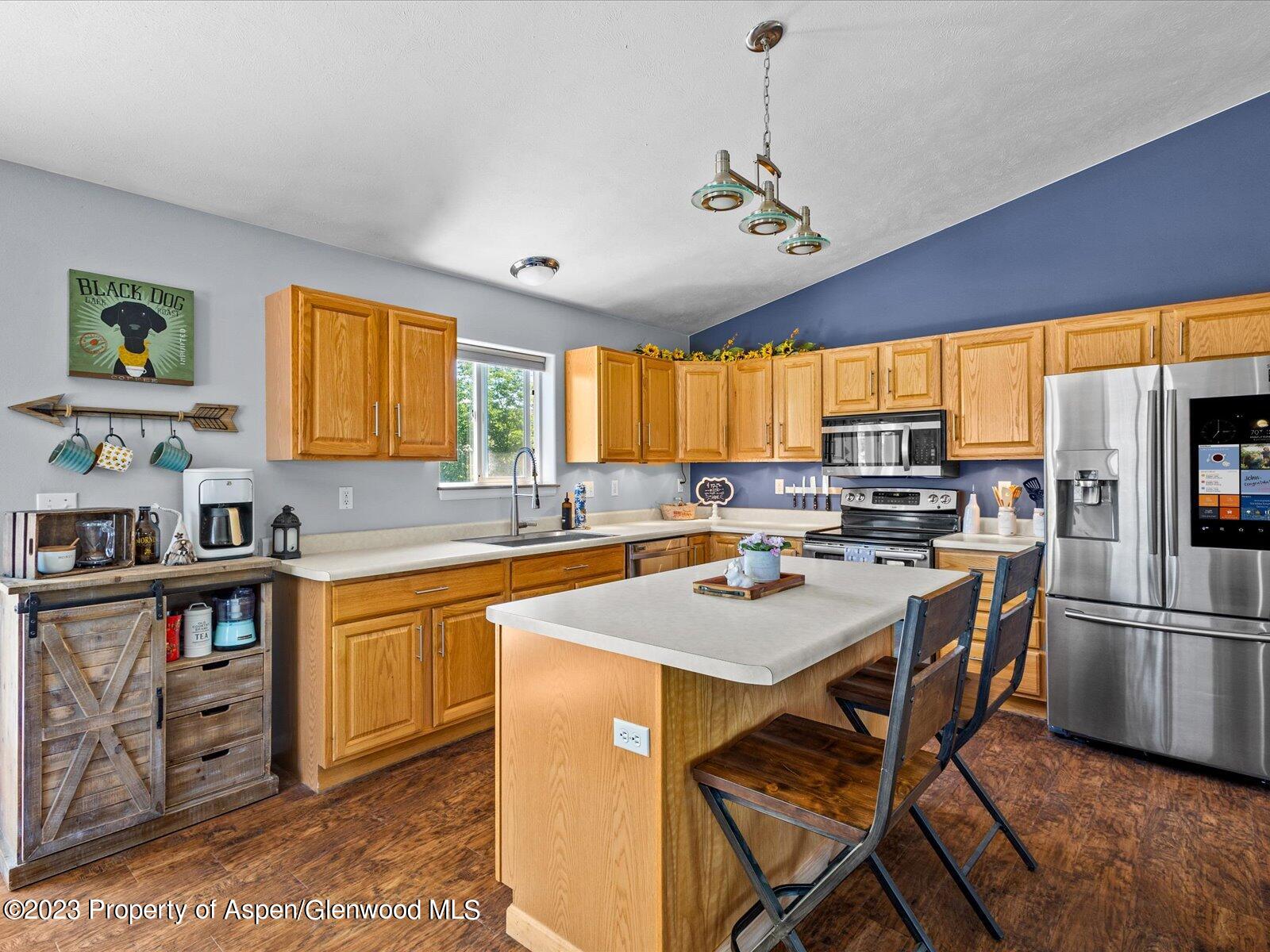 1562 Anvil View Avenue Rifle, CO 81650 - Photo 9 of 26 a kitchen with stainless steel appliances granite countertop a table chairs sink refrigerator and cabinets