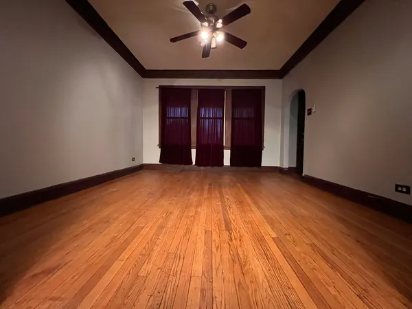 a view of empty room with wooden floor and fan