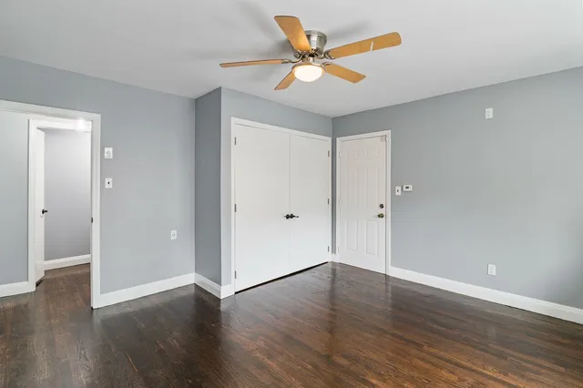 an empty room with wooden floor and a ceiling fan