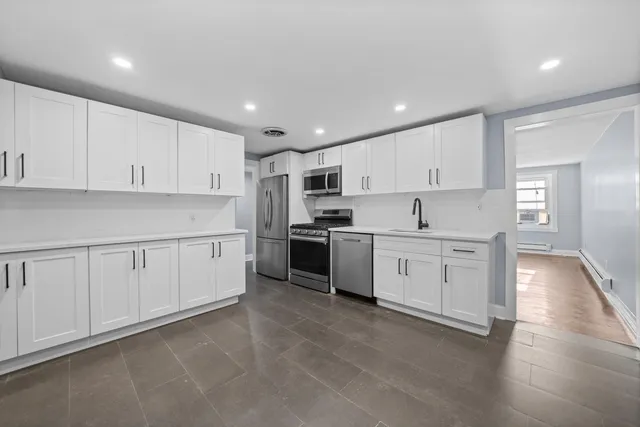 a kitchen with granite countertop white cabinets and stainless steel appliances