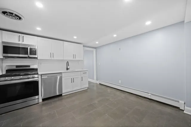 a large kitchen with stainless steel appliances granite countertop a stove a sink and a microwave