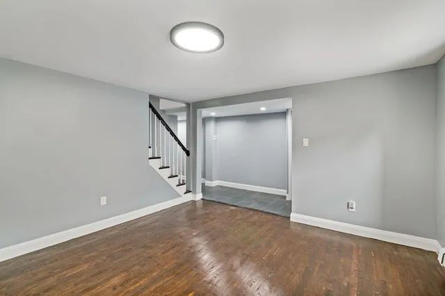 a view of an empty room with wooden floor and stairs