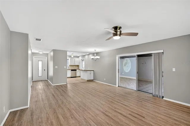 a view of an empty room with a window and wooden floor