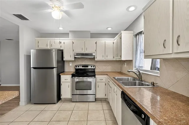a kitchen with a sink a refrigerator and white cabinets