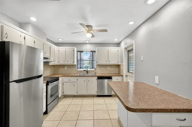 a kitchen with granite countertop a sink stainless steel appliances white cabinets and a window