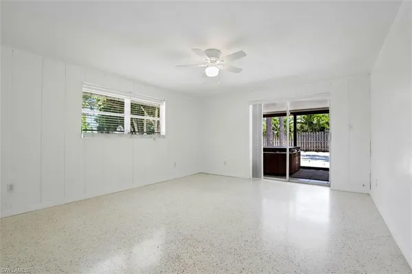 an empty room with windows and ceiling fan