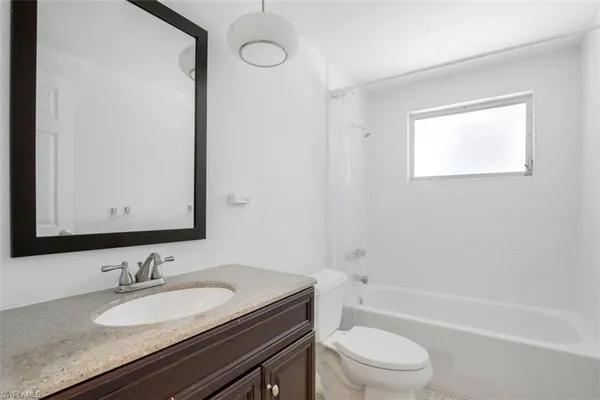 a bathroom with a granite countertop sink toilet a mirror and shower