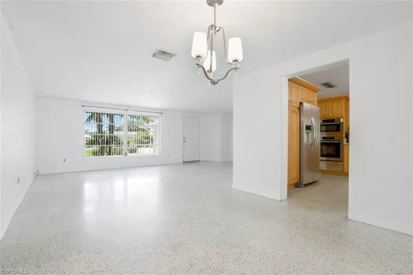 an empty room with chandelier fan and windows