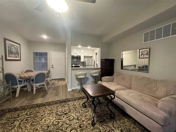 a living room with furniture and a dining table with wooden floor