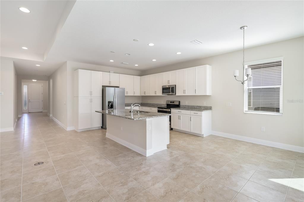 19803 Bridgetown Loop Venice, FL 34293 - Photo 13 of 51 a kitchen with stainless steel appliances kitchen island granite countertop a stove a sink a refrigerator and white cabinets with wooden floor