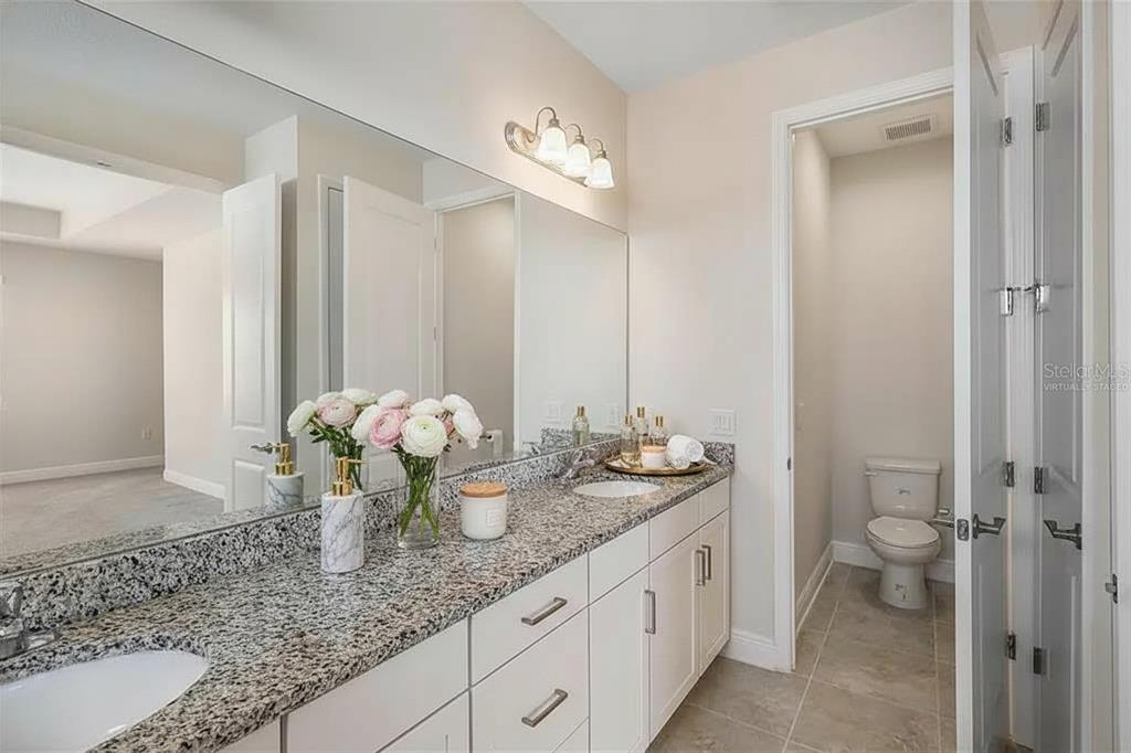 19803 Bridgetown Loop Venice, FL 34293 - Photo 49 of 51 a bathroom with a granite countertop sink a toilet and a mirror