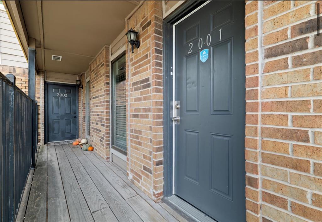 Entrance to property with a porch and brick siding