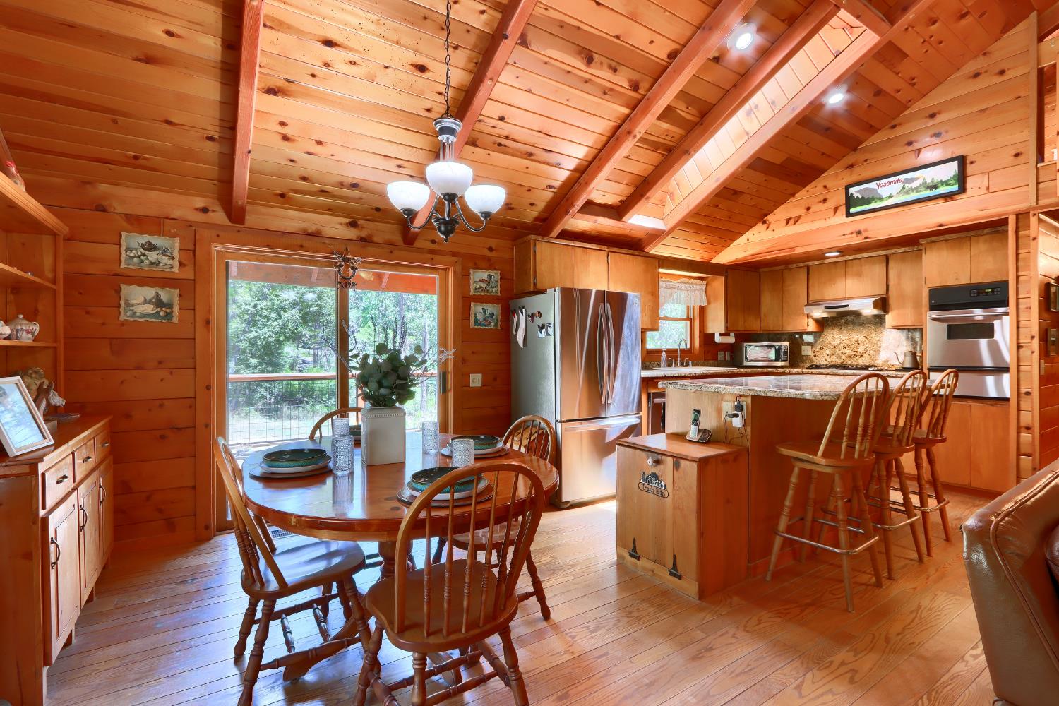 7190 Hites Cove Road Mariposa, CA 95338 - Photo 11 of 61 a dining room with stainless steel appliances a dining table wooden floor and a large window
