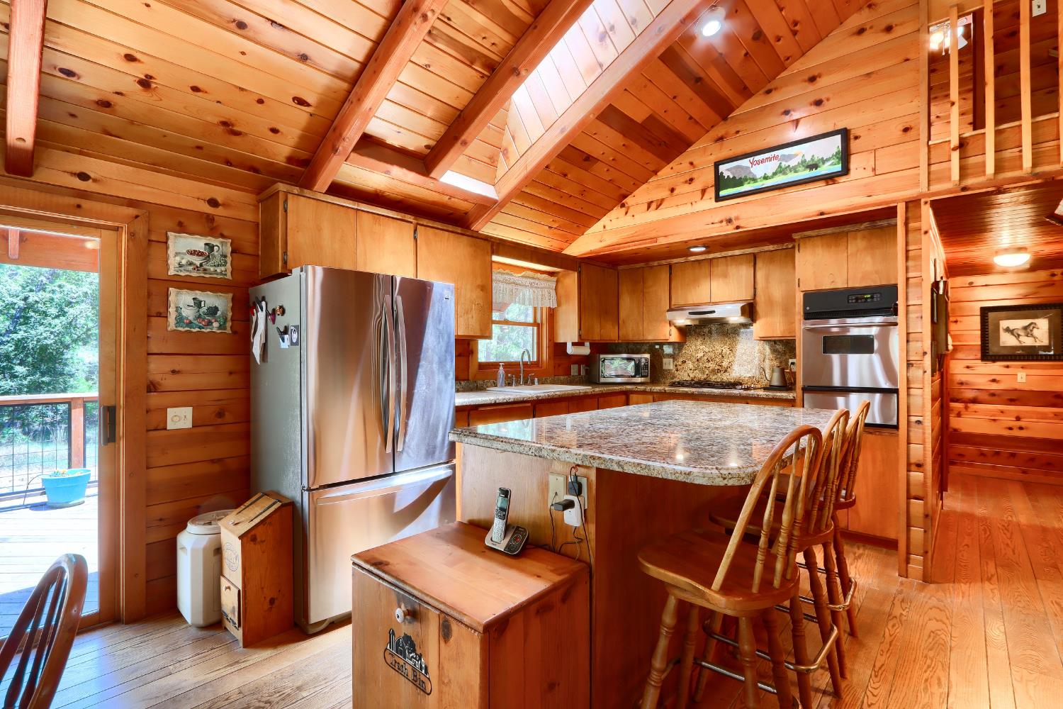 7190 Hites Cove Road Mariposa, CA 95338 - Photo 13 of 61 a kitchen with stainless steel appliances granite countertop a table chairs and a refrigerator