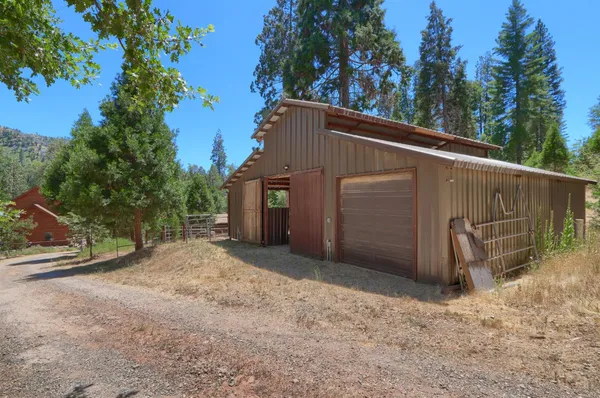 a view of a wooden house with a yard and sitting area