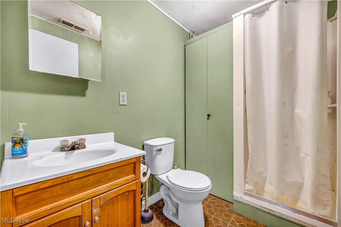 4032 Hanford Road Wakeman, OH 44889 - Photo 40 of 50 Bathroom with toilet, curtained shower, tile patterned floors, vanity, and a textured ceiling