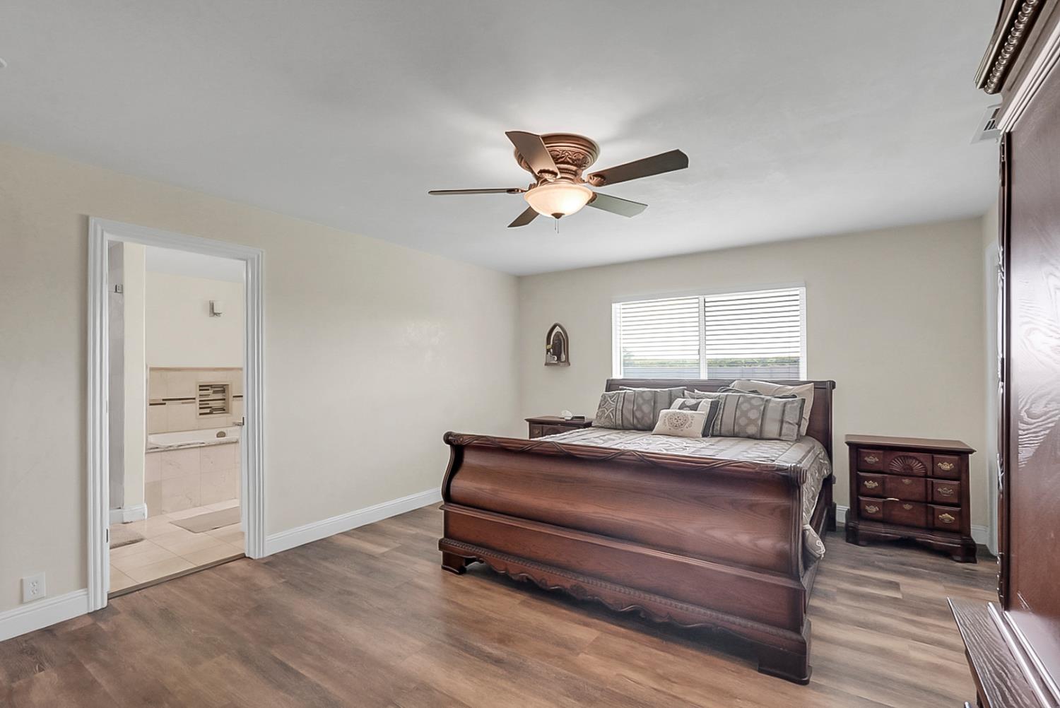 6112 Slaton Court Stockton, CA 95215 - Photo 16 of 46 a bedroom with a large bed a chandelier and a window
