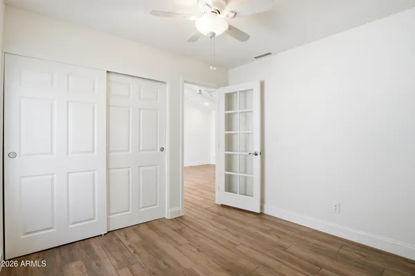 an empty room with wooden floor closet and windows