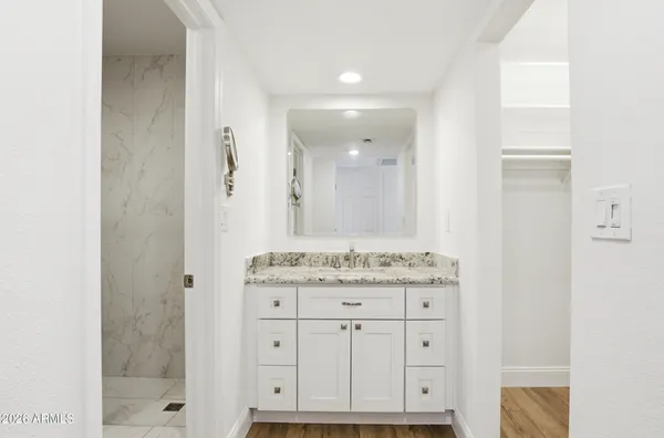 a bathroom with a granite countertop sink a mirror and a shower