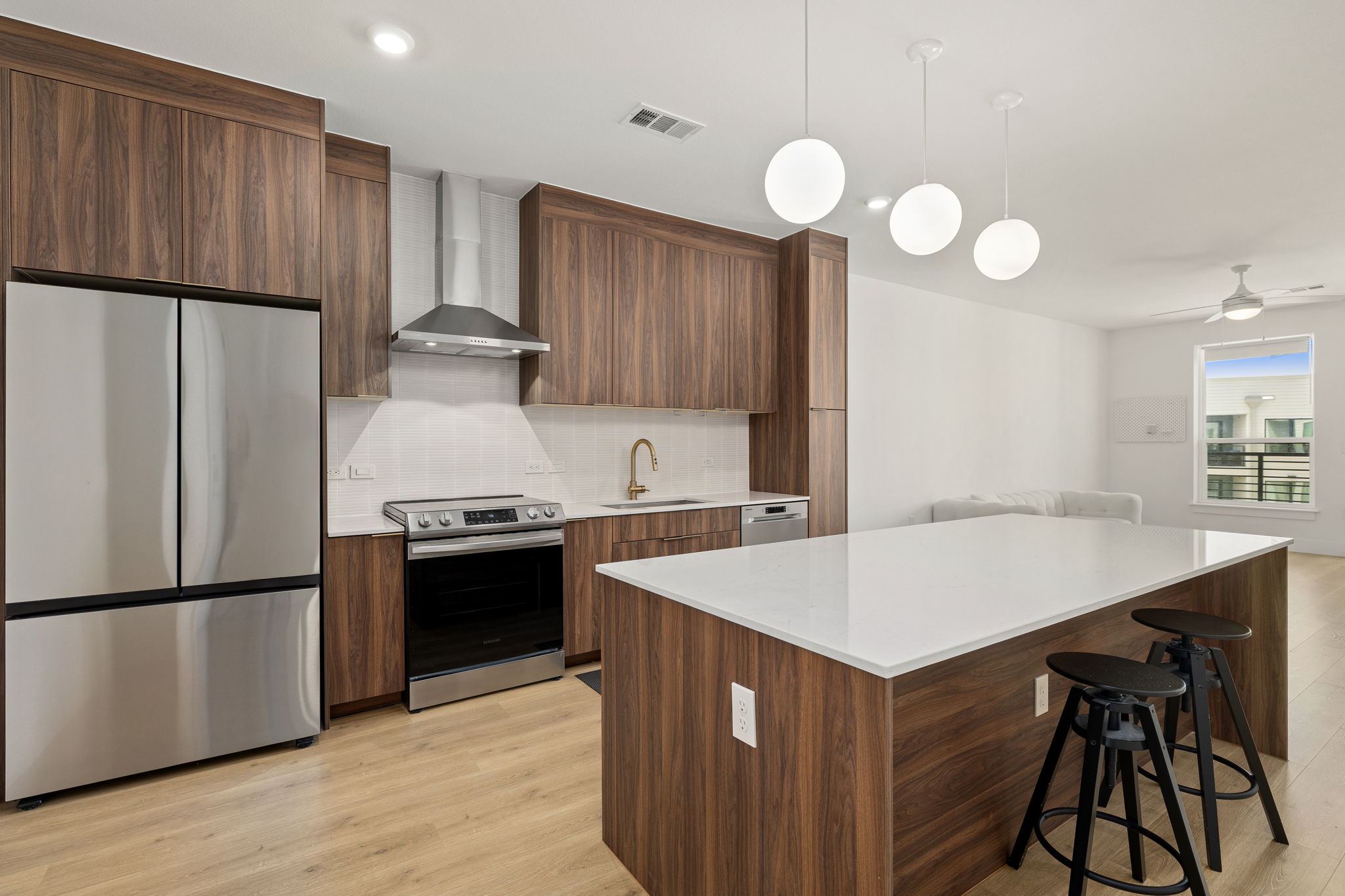 1701 Simond Avenue, Unit 612 Austin, TX 78723 - Photo 14 of 40 Contemporary kitchen featuring dark wood-finish cabinetry, stainless steel appliances, a white subway tile backsplash, and a large central island with a white countertop