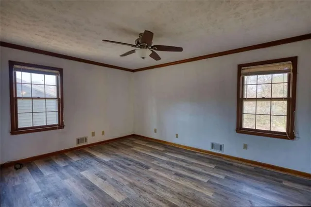 an empty room with windows and a ceiling fan