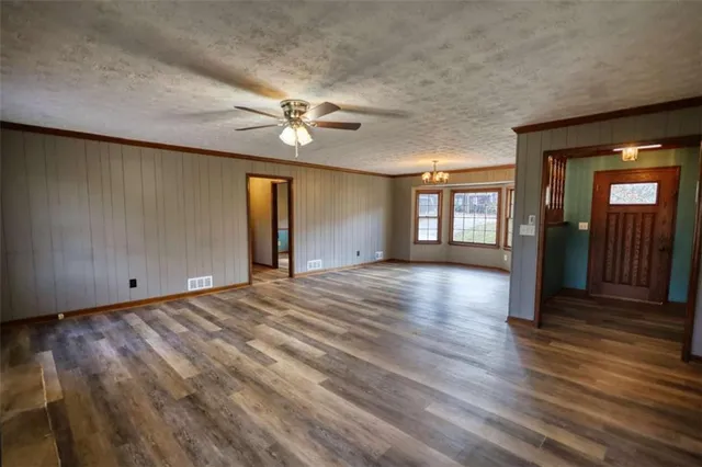 an empty room with windows a fireplace a ceiling fan and wooden floor