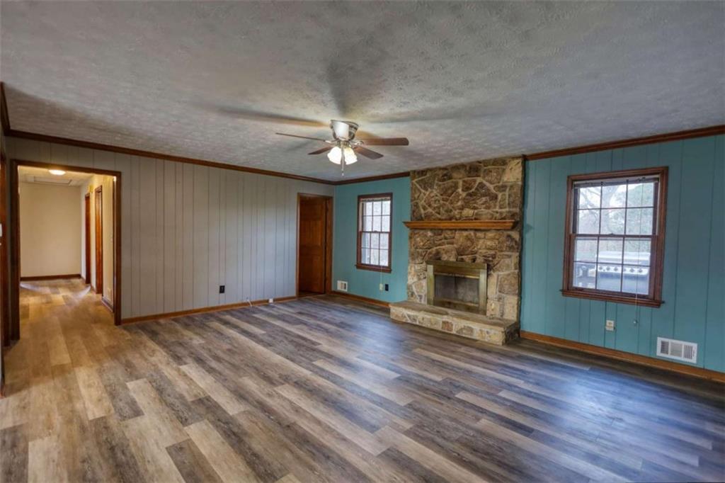 2289 Amberbrook Drive Southwest Conyers, GA 30094 - Photo 6 of 79 an empty room with windows a fireplace a ceiling fan and wooden floor