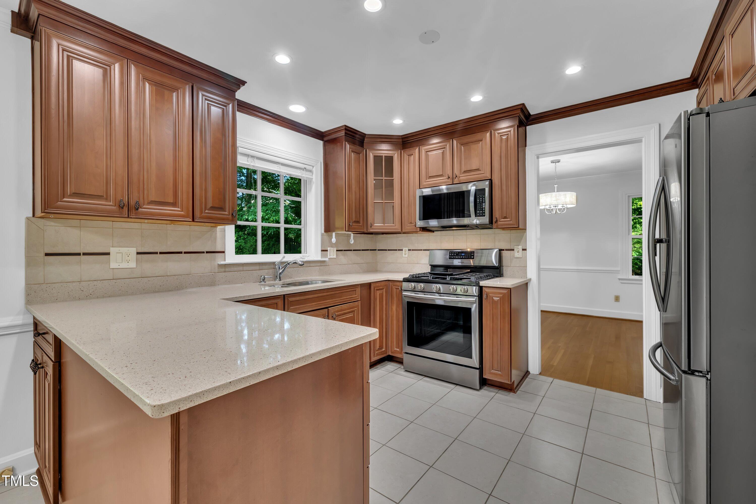2204 Basil Drive Raleigh, NC 27612 - Photo 10 of 49 a kitchen with a sink a counter top space stainless steel appliances and a window