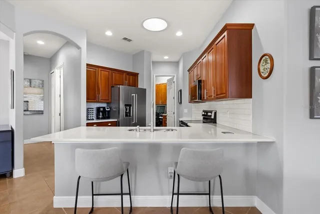 a kitchen with stainless steel appliances kitchen island granite countertop a refrigerator a stove top oven a sink and dishwasher