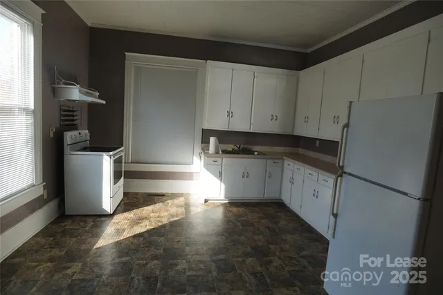 a kitchen with granite countertop white cabinets and refrigerator