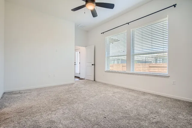 an empty room with chandelier fan and windows