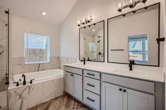 a bathroom with a two sinks a large mirror and a bathtub next to a window