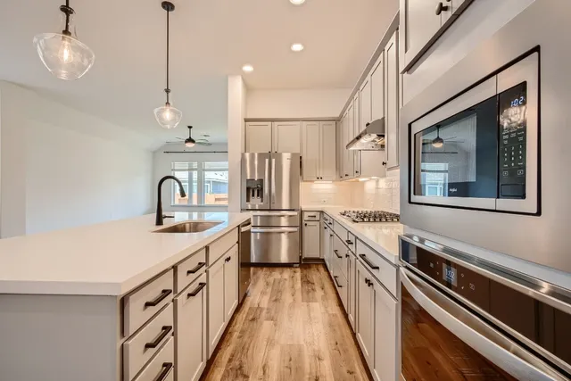 a kitchen with stainless steel appliances sink stove top oven and cabinets